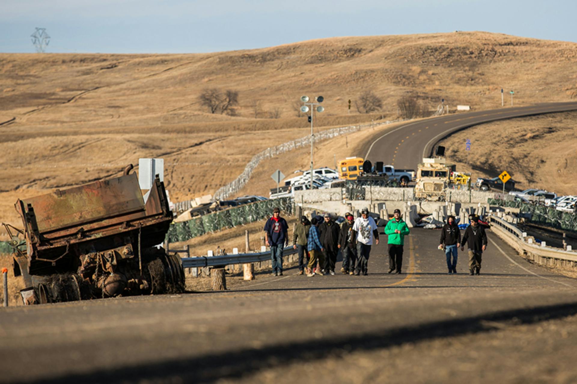 Standing Rock, North Dakota, November 26, 2016. Water protectors return from the Highway 1806 blockade north of the Oceti Sakowin Camp at Standing Rock as police look on from behind the concrete barriers. FrostOnFlower/iStock