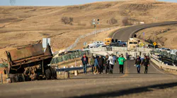 Standing Rock, North Dakota, November 26, 2016. Water protectors return from the Highway 1806 blockade north of the Oceti Sakowin Camp at Standing Rock as police look on from behind the concrete barriers. FrostOnFlower/iStock