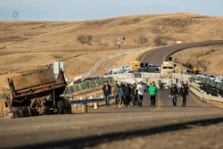 Standing Rock, North Dakota, November 26, 2016. Water protectors return from the Highway 1806 blockade north of the Oceti Sakowin Camp at Standing Rock as police look on from behind the concrete barriers. FrostOnFlower/iStock
