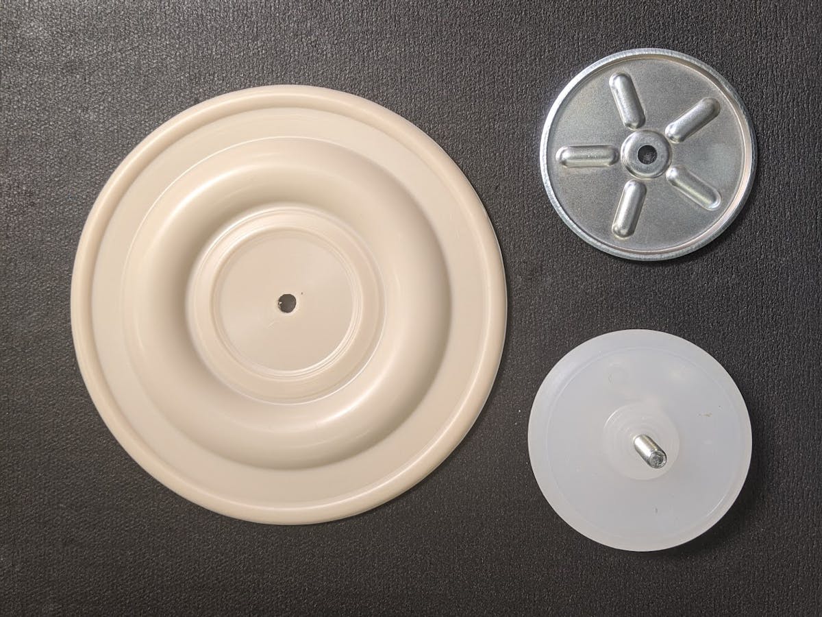 A Santoprene diaphragm with metal inner plate and outer plastic plate.