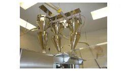 A sanitary vacuum conveyor keeps a tablet press filled in a pharmaceutical environment.