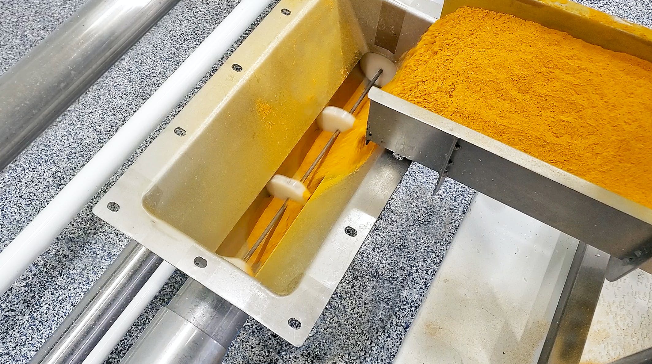 A tubular cable drag conveyor uses a cable with discs attached at set intervals within a tube to gently pull powder from inlet to discharge.