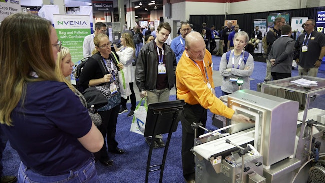 A Powder Show exhibitor demonstrates equipment to attendees on the show floor.