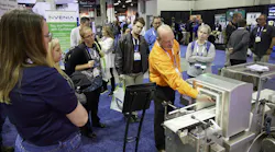 A Powder Show exhibitor demonstrates equipment to attendees on the show floor.