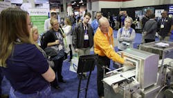 A Powder Show exhibitor demonstrates equipment to attendees on the show floor. A Powder Show exhibitor demonstrates equipment to attendees on the show floor.