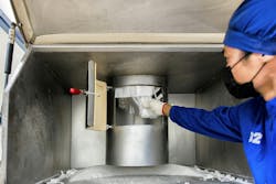 A worker pulls the bulk bag outlet spout through a 380-mm (15-in.) diameter iris valve, which closes around the spout, preventing material flow. A worker pulls the bulk bag outlet spout through a 380-mm (15-in.) diameter iris valve, which closes around the spout, preventing material flow.