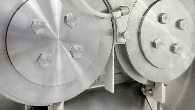 Roll compactor discharging a ribbon of compressed material.