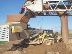 A front loader clears spillage from a transfer point. A front loader clears spillage from a transfer point.
