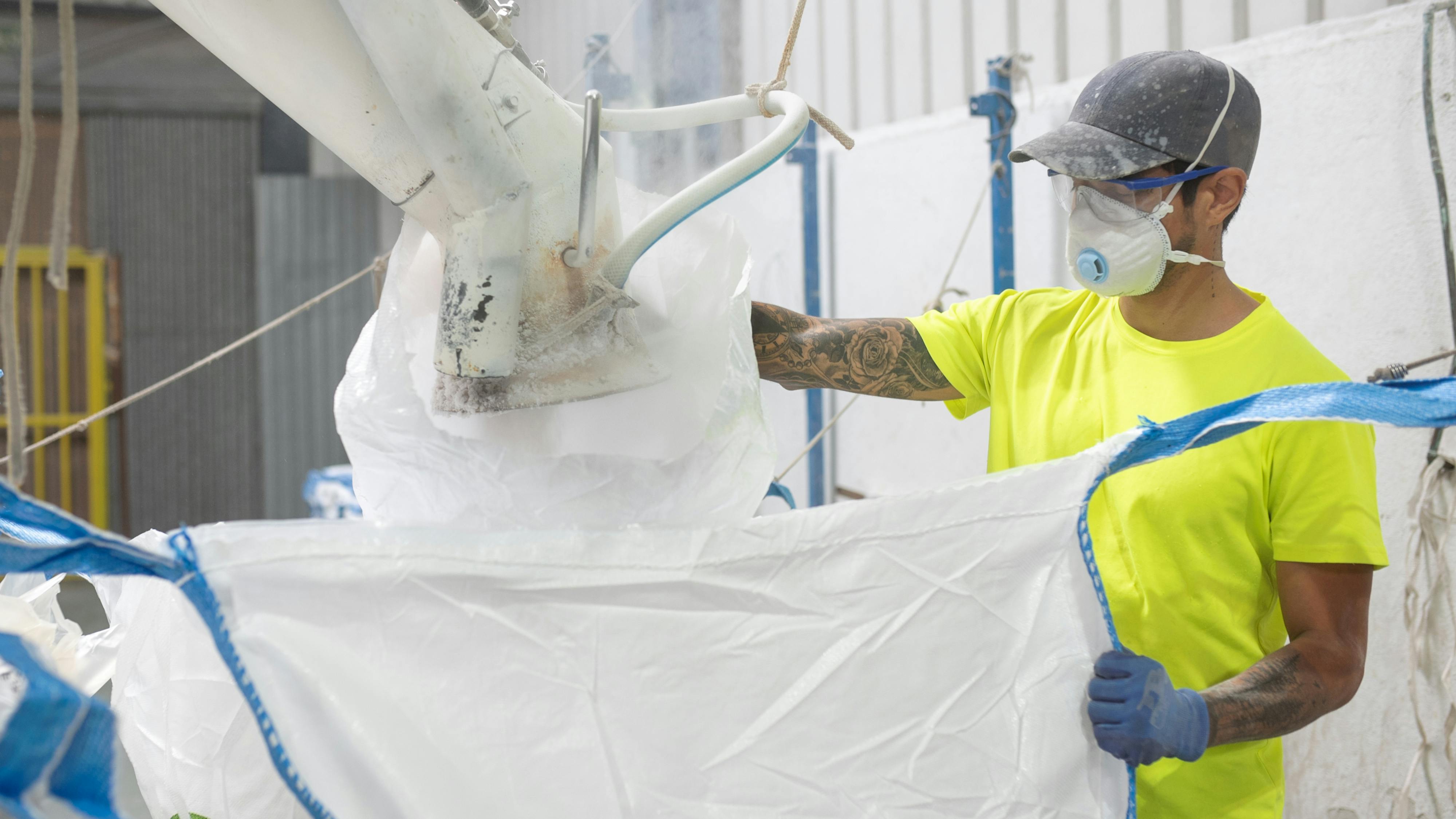 Worker filling bulk bag with mask and dust
