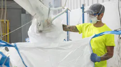 Worker filling bulk bag with mask and dust