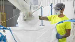 Worker filling bulk bag with mask and dust